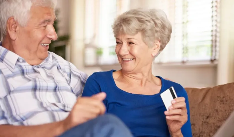 Two elderly people sitting together and looking at financial documents, appearing to discuss or review payments for care.