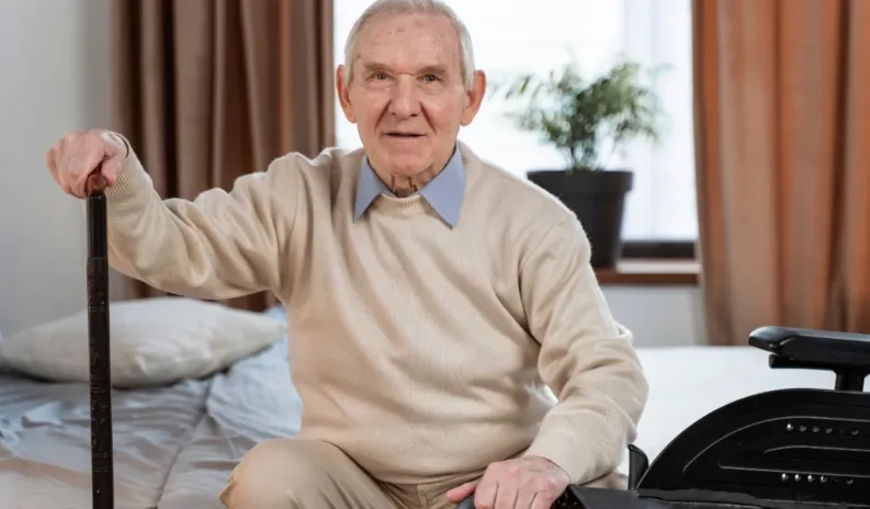 Older man with a walking stick and wheelchair, demonstrating mobility assistance and travel support for elderly people.