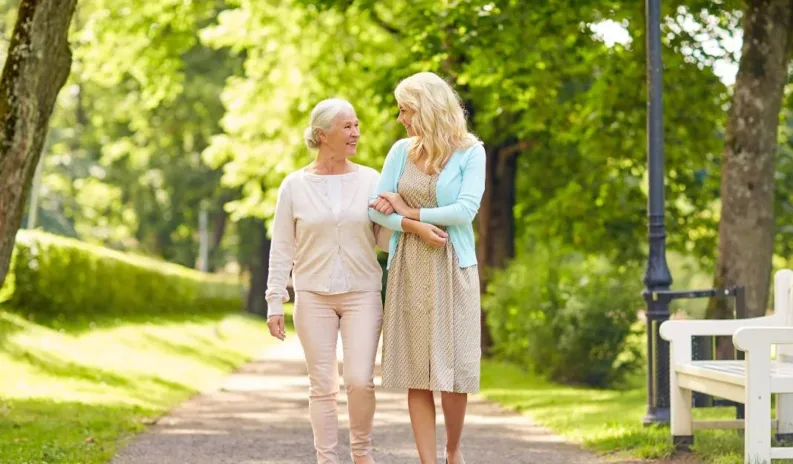 Professional companion carer walking alongside an older adult outdoors to promote wellbeing, independence and companionship.